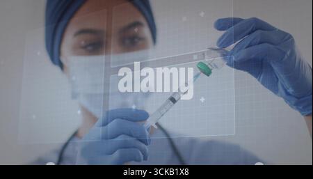 Infirmière asiatique en gommage bleu tirant le médicament dans la seringue du flacon à la clinique, superposition holographique Banque D'Images