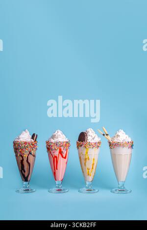 Milkshakes colorés servis dans des verres sur fond bleu, boissons sucrées rafraîchissantes parfaites pour l'été, conception de menu et publicité alimentaire. Banque D'Images