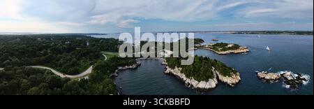 Vue aérienne de la côte rocheuse rencontrant la mer bleue profonde, contrastée par les forêts verdoyantes de Fort Wetherill, Jamestown, Rhode Island, États-Unis. Banque D'Images