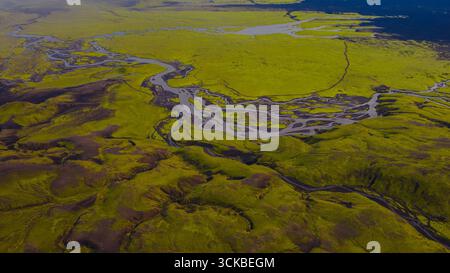Image aérienne d'un terrain volcanique couvert de mousse verte en Islande, intersecté par des rivières tressées. Les rivières forment des motifs complexes au milieu d'un volcanique sombre Banque D'Images