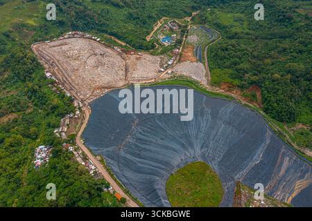 Vue aérienne d'un grand site d'enfouissement entouré de verdure. Banque D'Images
