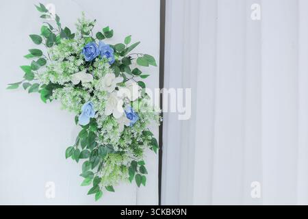 Un arrangement floral avec des roses bleues et blanches avec de la verdure sur un fond blanc Banque D'Images