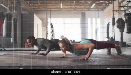 Exécution de pompes partenaires d'entraînement portant des vêtements de sport sur un tapis en caoutchouc dans la salle de gym, avec des sacs de frappe. Force, travail d'équipe, forme physique, motivation, exercice, w Banque D'Images