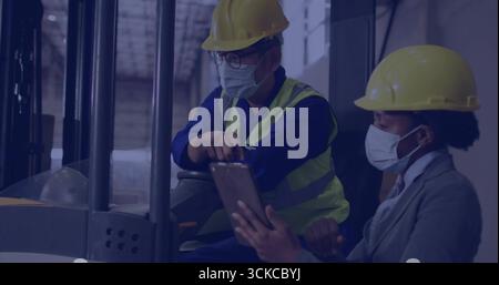 Les collègues utilisant un chariot élévateur examinant la tablette dans l'entrepôt avec des casques de sécurité jaunes, gilet réfléchissant. Industriel, travail d'équipe, sécurité, professionnalisme, mac Banque D'Images