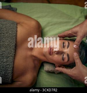 Thérapeute masculin Reiki faisant un traitement à une belle jeune femme adulte caucasienne. Massage sans contact physique. Vue de dessus. Banque D'Images