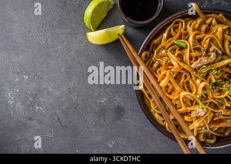 Pâtes végétariennes asiatiques, nouilles udon faites maison avec champignons shiitake sautés, sésame et légumes, sauce soja et citron vert, copie de fond gris foncé Banque D'Images