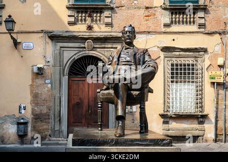 Statue en bronze du compositeur Puccini, représentée dans une pose détendue sur une chaise, cigarette à la main à Lucques, en Italie. Banque D'Images