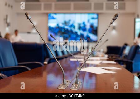 Salle de conférence vide avec microphones et configuration d'écran vidéo. Banque D'Images