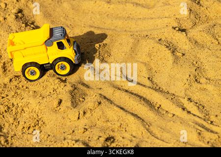 voiture jaune jouet dans bac à sable, gros plan. Banque D'Images