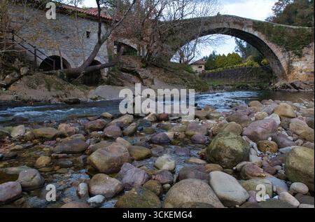 Pont médiéval historique au-dessus d'une rivière rocheuse - Une photo à angle bas d'un pont de pierre historique avec une grande arche, enjambant une rivière calme remplie de roc Banque D'Images