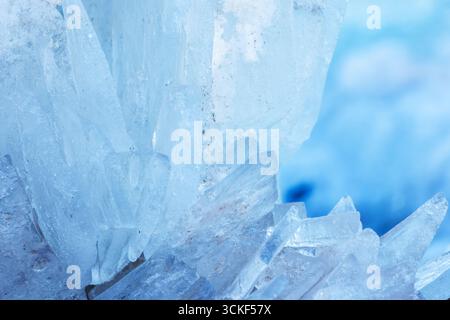 Plan macro mettant en évidence des formations de cristaux de glace translucides dans des teintes bleues hivernales, soulignant la sérénité et la beauté naturelle. Photo de fond naturel Banque D'Images