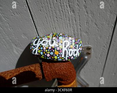 Tu roches la roche de gentillesse sur un tuyau en métal rouillé Banque D'Images