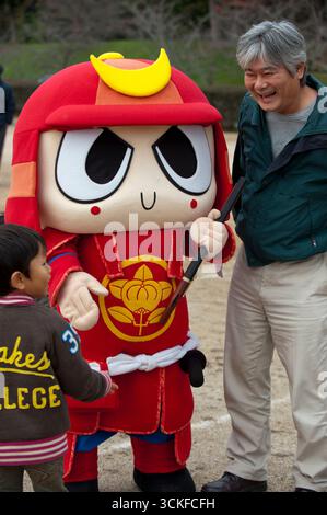 Les personnes interagissant avec la mascotte japonaise yuru-kyara personnage de culture populaire Hikodon (casque kabuto samouraï avec arme à feu) lors de l'événement à Hikone, Shiga, Japon. Banque D'Images