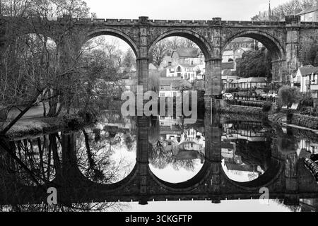 Viaduc de chemin de fer en pierre enjambant la rivière Nidd à Knaresborough reflété dans l'eau en noir et blanc Banque D'Images