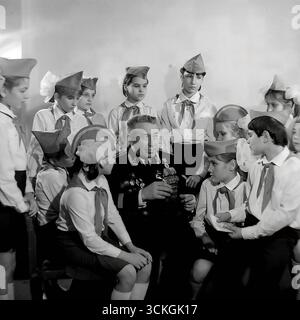 Une « leçon de courage » à l'école secondaire n ° 12 à Sloviansk à la fin des années 1970 L'instructeur militaire de l'école (voenruk), un vétéran distingué de la Grande Guerre patriotique, est entouré d'étudiants d'un club patriotique, tous en uniforme. Il leur montre ses récompenses militaires et partage les histoires derrière eux. Cette photographie symbolise profondément le système soviétique de formation militaire de base (NVP) et les vastes programmes d'éducation patriotique conçus pour inculquer le respect de la mémoire militaire et historique à la jeune génération Banque D'Images