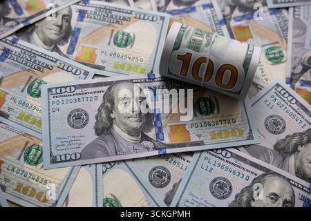 Répartition de billets de cent dollars avec pile roulée. Gros plan d'une pile de billets de cent dollars, présentant les dessins détaillés de Benjamin Franklin Banque D'Images
