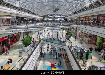 Une vue intérieure animée du centre commercial Centro Vasco da Gama à Lisbonne, avec plusieurs étages, un toit en verre et des gens animés sur le Banque D'Images