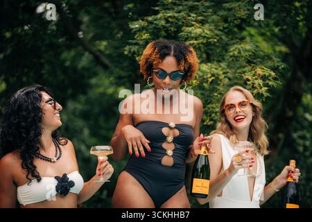 Amis dégustant du champagne au bord de la piscine en vacances d'été Banque D'Images
