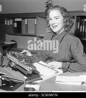 Dans les années 1950, une employée de bureau exploite une machine à cartes perforées, saisissant des informations sur des cartes perforées. Les cartes perforées étaient un support de stockage où les trous perforés dans la carte représentaient des données d'entrée, qui étaient ensuite lues par un lecteur de cartes perforées pour organiser ou imprimer les informations. Technologie des cartes perforées : dans les années 1950, les cartes perforées étaient une pierre angulaire de l'informatique précoce, utilisée pour le traitement des données dans les entreprises et les bureaux gouvernementaux. Cette technologie, lancée par des entreprises comme IBM, était un précurseur des bases de données numériques modernes. L'image capture un moment de la vie de bureau du milieu du XXe siècle, attrayant pour t Banque D'Images