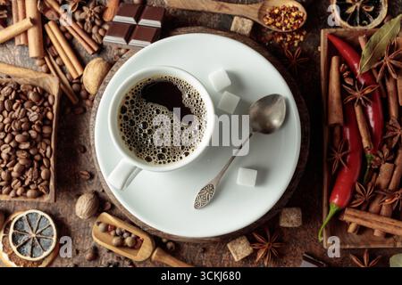 Diverses épices et assaisonnements pour faire des boissons aromatiques à base de café. Café noir dans une tasse blanche. Vue de dessus. Banque D'Images
