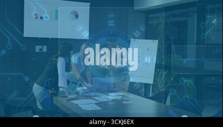 Examen des graphiques imprimés et utilisation d'un ordinateur portable pendant que l'équipe collabore dans la salle de réunion, avec superposition 6G. Banque D'Images