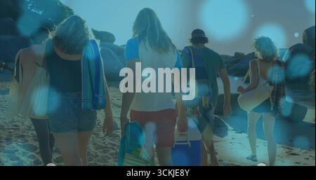 Cinq amis marchant vers le rivage sur la plage de sable, avec des serviettes refroidisseur tableau fourre-tout sacs tapis de plage Banque D'Images
