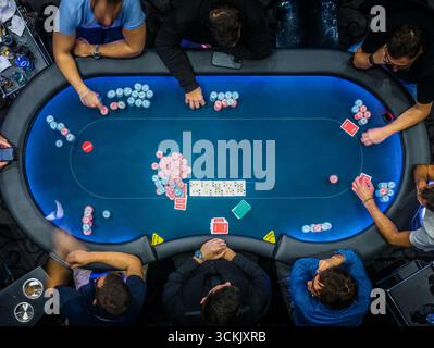 Vue de haut en bas d'un jeu de poker à enjeux élevés dans un casino avec des joueurs engagés dans des stratégies sérieuses et une concentration intense Banque D'Images