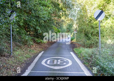 Entrée dans une voie de campagne étroite avec un panneau de limitation de vitesse nationale sur enrty. Banque D'Images