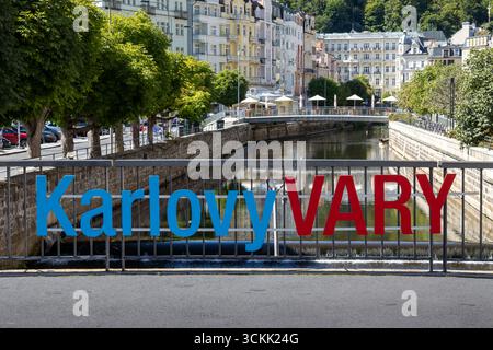 Centre-ville avec un pont traverser la rivière Ohre. Panneau Karlovy Vary sur la clôture. Promenade avec des arbres et des buidlings historiques sur les deux rives. Banque D'Images