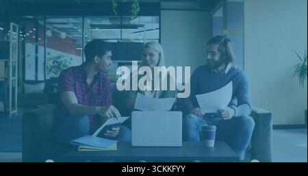 Collaboration collègues examinant des documents dans le salon de bureau avec ordinateur portable, tasse à café, ordinateur portable Banque D'Images