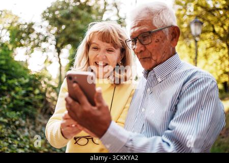 Moments joyeux et mémorables les aînés partagés s'engagent avec la technologie dans les grands espaces Banque D'Images