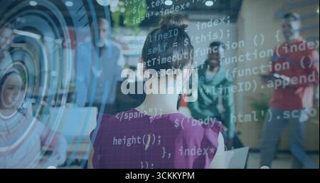 Développeur de démonstration en blouse rose tapant code avec des observateurs dans le bureau, avec ordinateur portable et HUD Banque D'Images