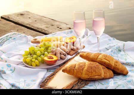 deux verres de champagne et de fruits sur une plate-forme en bois près de l'eau. pique-nique. Banque D'Images