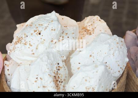 28 août 2025, Bruges, Belgique — gros plan de grandes meringues blanches saupoudrées de noix concassées exposées dans un panier. Banque D'Images