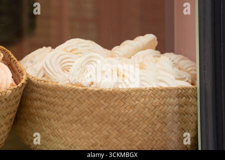 28 août 2025, Bruges, Belgique — Un panier en osier rempli de tourbillons de guimauve blanche saupoudrés de poudre de sucre. Banque D'Images