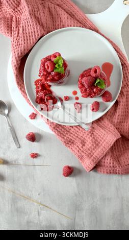 Une vue magnifique de haut en bas de deux puddings crémeux aux graines de chia, généreusement recouverts d'un riche coulis de framboises et de framboises fraîches. Les desserts sont pr Banque D'Images