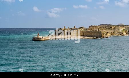 Vue sur Fort Ricasoli et le phare East Breakwater à l'entrée du Grand Port à la Valette, Malte. Banque D'Images