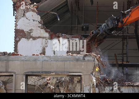 Excavatrice démolit un bâtiment pour la reconstruction à Sofia, Bulgarie. Démolition d'un mur de briques d'un bâtiment ancien Banque D'Images