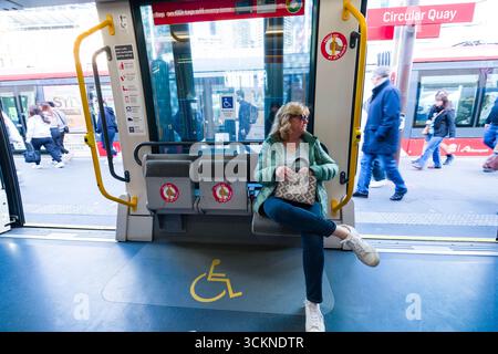 Une femme mature est assise dans un véhicule de transport en commun à Circular Quay, observant les environs animés des gens et de la vie urbaine, Sydney Banque D'Images