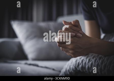 les mains de la femme se serrèrent dans un moment de prière ou de contemplation profonde mettant en valeur les pensées intérieures. Banque D'Images