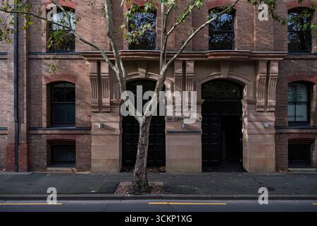 Un bâtiment historique en briques avec de grandes fenêtres cintrées, avec une entrée modernisée entourée d'un paysage urbain résidentiel, Sydney Banque D'Images