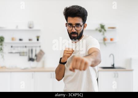 Homme pratiquant les techniques de boxe dans un environnement de cuisine avec détermination Banque D'Images