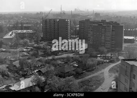 Une vue panoramique du développement dans le quartier de Svobody Street à Slovyansk au cours des années 1980 Cette prise de vue aérienne saisissante capture un immeuble de plusieurs étages en construction, créant un contraste frappant avec l'ancien secteur du logement privé au premier plan et le paysage industriel tentaculaire à l'horizon. Cette image est un symbole puissant de la dernière vague du développement urbain soviétique et de la vie paisible et créative dans le Donbass, une époque où la ville était activement en croissance et construisait des maisons modernes pour ses résidents Banque D'Images