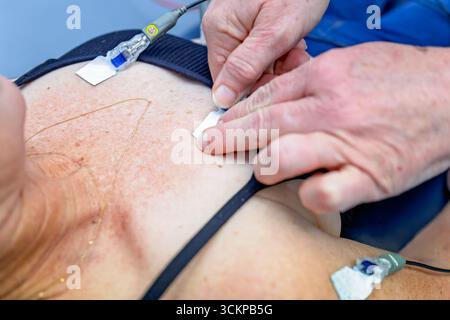 L'infirmière appliquant l'ECG mène à la patiente, médecin généraliste australien, clinique médicale Banque D'Images