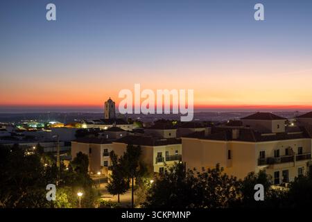 Paysage de ville côtière au crépuscule, avec une architecture illuminée et une tour de l'horloge, avec un magnifique ciel de coucher de soleil créant un guichet automatique serein et pittoresque Banque D'Images