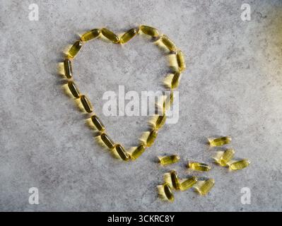Capsules d'huile de poisson disposées dans un cœur géant Banque D'Images