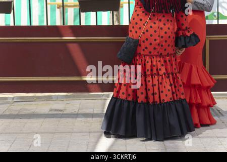 Deux femmes portant des robes traditionnelles de flamenco rouge et noire se tiennent ensemble, mettant en valeur la culture vibrante de la feria de abril à ronda, dans le mal Banque D'Images