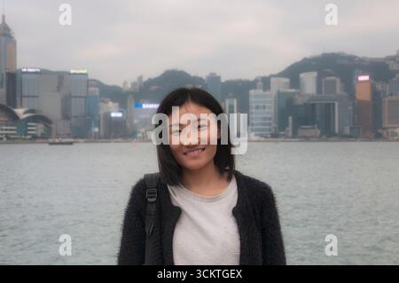 une femme chinoise heureuse avec les nouveaux territoires de hong kong et la baie de kowloon à hong kong en chine par un jour couvert. Banque D'Images