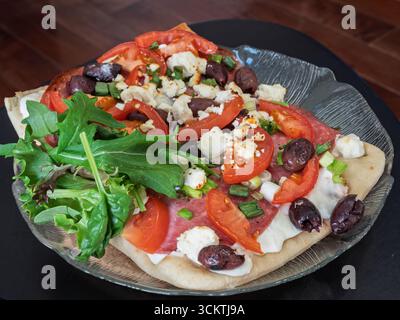 Une vue de haut en bas d'une délicieuse pizza gastronomique faite maison avec des ingrédients frais sur une planche à découper en bois rustique. Banque D'Images