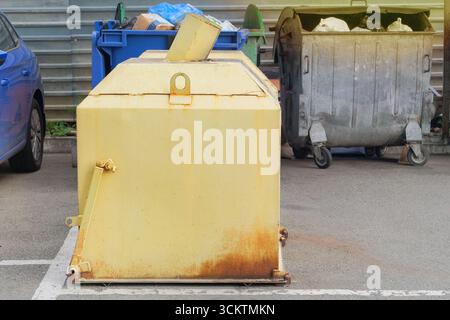 Poubelle jaune métallique. Ordures, lots de déchets, décharges. Les bennes à ordures sont pleines de déchets. Banque D'Images